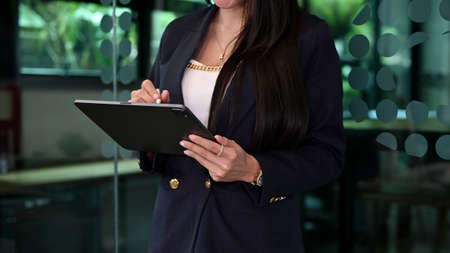 Cropped image, Professional businesswoman or female manager in formal suit standing in the office and checking some information on the report.の写真素材