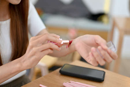 Attractive young Asian woman testing a lipstick on her arm. close-up hands image, Female makeup artist testing a lipstick.の写真素材