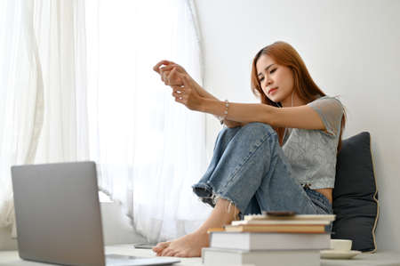 Sad and unhappy young Asian woman listening a sad song with her earphones in the living room, having...