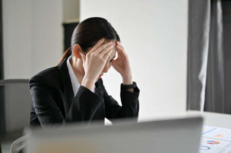 Stressed young Asian businesswoman or financial worker having a problem on her financial work, getting trouble or complain from her boss.の写真素材