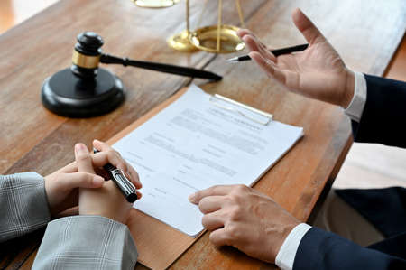 A professional adult male lawyer or legal business consultant counsels and meets with his client to...