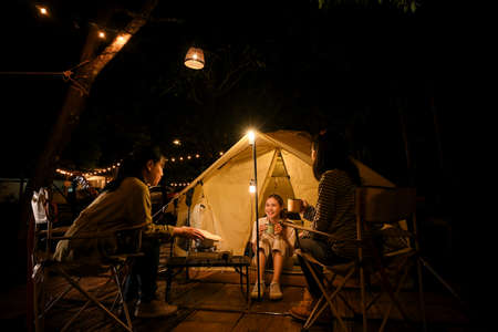 A group of an Asian female teenagers enjoy camping, talking, and looking at the stars at night together at the campground. Outdoor activity conceptの写真素材