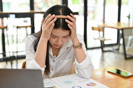 Stressed millennial Asian female office worker or businesswoman crying at her desk, feeling fail and...
