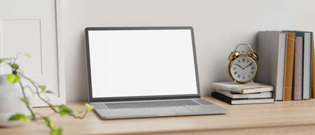 Minimal workspace on wood tabletop over white wall with laptop blank screen mockup, stack of book, alarm clock and decor plant. 3d rendering, 3d illustrationの写真素材