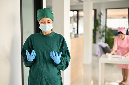 Professional and expert Asian female surgeon in green surgical gown and medical mask success with her surgery, standing in front of the Operating room.の写真素材