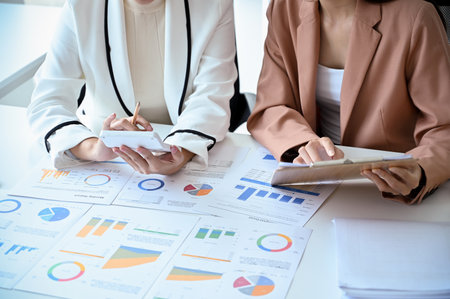 Two professional businesswomen or female financial analysts are working on a financial analysis project together in the office. cropped imageの写真素材