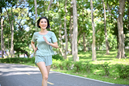 Active and fit millennial Asian female running and jogging in the morning at the city park. Healthy lifestyle conceptの写真素材