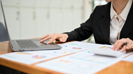 Professional Asian businesswoman or financial consultant planning a financial strategy, working on her financial report at her desk. cropped imageの写真素材