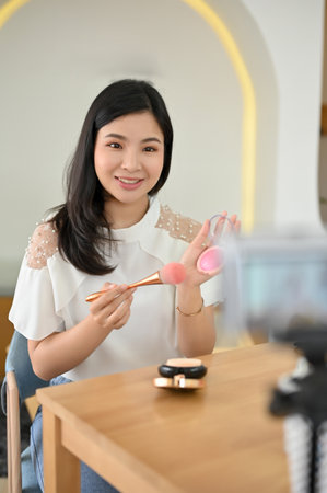 Portrait, Gorgeous young Asian female beauty blogger recording her beauty makeup video on camera, and sharing her favourite cosmetic to her online followers.の写真素材