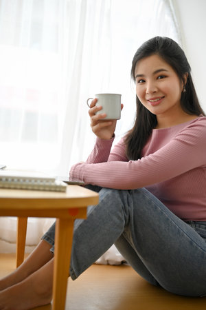 Portrait, Attractive and pretty young Asian woman relaxing in a beautiful cafe while sipping a warm coffee or cocoa.の写真素材