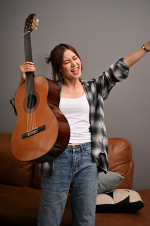 Portrait, Attractive hipster young Asian woman in the living room holding her classic guitar. Activity and leisure conceptの写真素材