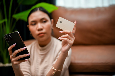 A gorgeous Asian female holding a smartphone and a credit card. Online payment, online shopping,...