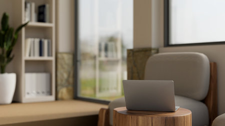 A laptop computer is on a wooden side table in the modern and comfortable office waiting room....