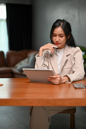 Portrait, Professional millennial Asian businesswoman or female entrepreneur concentrating on her business tasks on her tablet.の写真素材