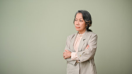 Unsatisfied, unhappy and upset 60s aged Asian woman or businesswoman, looking away from camera, arms...