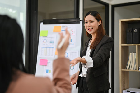 Attractive and professional millennial Asian businesswoman or female boss lead the meeting, discussing and sharing ideas with her team.の写真素材
