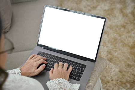 Above view, A female relaxes using a notebook laptop computer in her minimal comfortable living room. Laptop white screen mockup.の写真素材