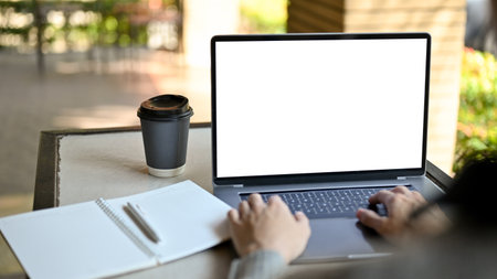 Male freelancer remote working at the coffee shop, using his laptop computer, typing on keyboard....