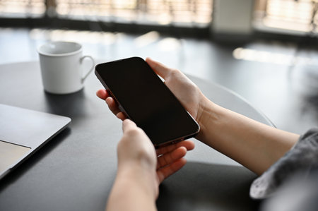 close-up image, A female holding her smartphone over a table, relaxing sitting in the coffee shop.