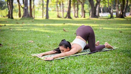 Attractive and charming Asian woman in sportswear stretching and practicing yoga in the beautiful...