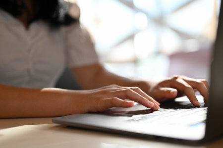 Young Asian female freelancer or college student typing on keyboard, using laptop, remote working at...
