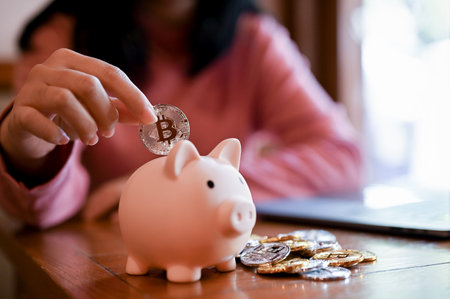 close-up image, Young Asian woman insert golden bitcoin into a pink piggy bank. investment and money...
