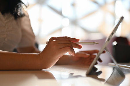 Asian female freelance graphic designer using her digital tablet and stylus pen to design her...