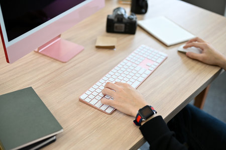 Professional male photographer working at his desk, using computer to adjust his picture on the program. cropped and close-up imageの写真素材