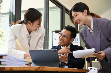 Team of professional and cheerful millennial Asian businesspeople working together in the office, discussing on their new project, sharing their creative ideas for new campaign.の写真素材