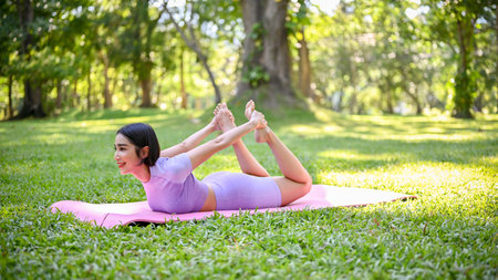 Healthy young Asian female in sportswear practicing yoga on yoga mat, posing advance yoga pose,...