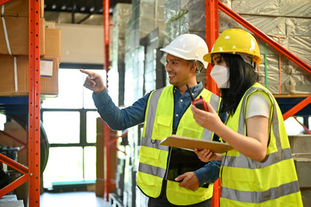 Smart and professional millennial Asian male warehouse supervisor training and working with a young...
