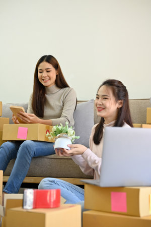 Portrait, Two young Asian female startup online small shop owners working together at home,...