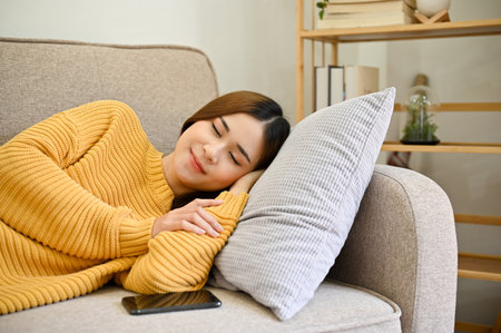 Beautiful young asian female relaxes sleeping, having a good dream or taking nap on her comfy couch...