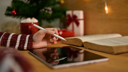 close-up image, A female in cozy sweater using her digital tablet, working at her desk in Christmas theme.の写真素材