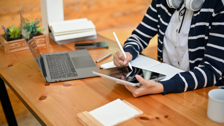 A female freelancer or college student using digital tablet, using stylus pen to draw or design her artwork on tablet. cropped shotの写真素材