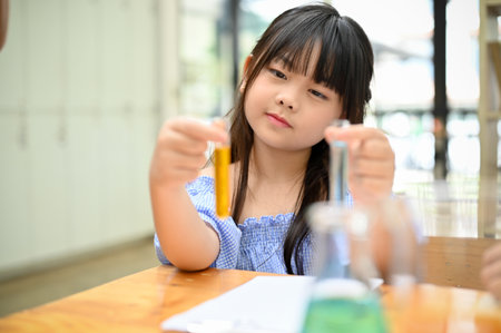 Lovely cute young Asian girl holding text tubes, doing an interesting science experiment for kids. Kids' and scientific activity conceptの写真素材