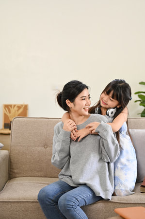 Portrait, Lovely Asian mom and little young daughter playing, relaxing and spending time together in their living room.の写真素材