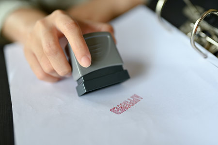 Professional businesswoman approved a business proposal with a rubber stamp on a document. close-up imageの写真素材