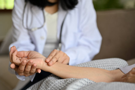 Cropped shot, Professional Asian female doctor checking pulse of her patient. Medical and health care conceptの写真素材