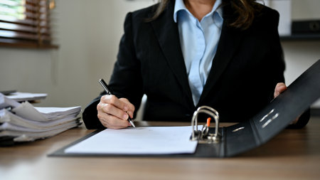 Professional Asian-aged businesswoman or female senior account manager in a formal suit, sign her signature on a document. cropped imageの写真素材