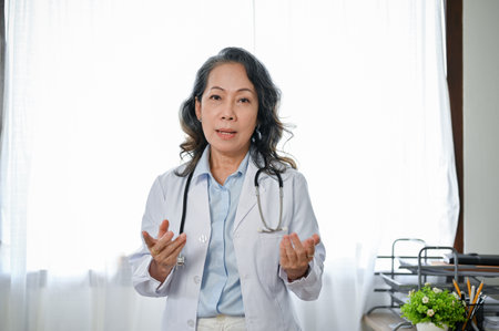 Professional Asian senior female doctor or physician in white gown uniform is explaining some medical advice.の写真素材