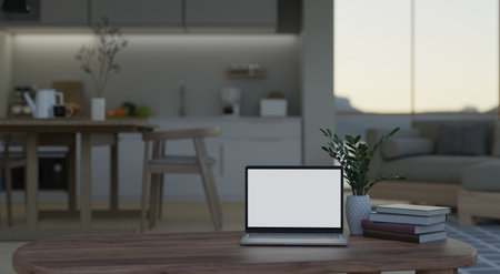 Home workspace with laptop white screen mockup, books and decor on wooden coffee table over blurred background of modern kitchen and dining room. 3d render, 3d illustrationの写真素材