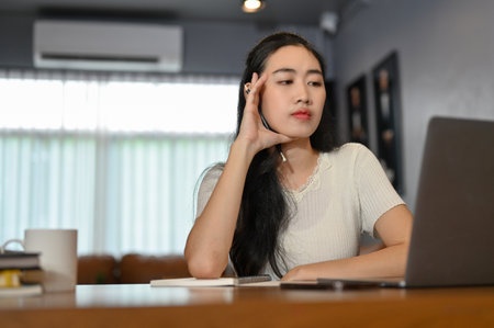 Attractive and confident young Asian female working in the living room, pensively planning her...
