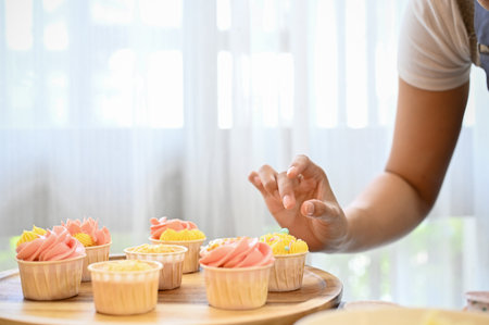 Cropped shot of woman decorating cupcake, making cupcake in her free time in kitchenの写真素材