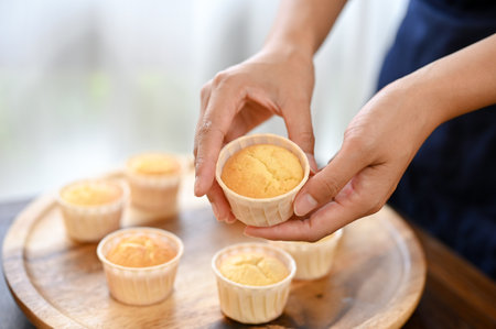 Close up view of woman showing fresh baked cupcake to the camera, making cupcakeの写真素材