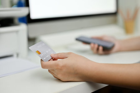close-up image, A female hand holding a credit card at her office desk. mobile banking, cashless payment, credit card paymentの写真素材