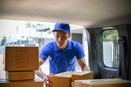 Young Asian delivery man in blue uniform organizing packages before handing package to customersの写真素材