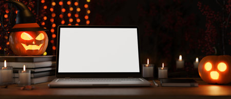 Modern dark working space or office desk with halloween decor, laptop white screen mockup, candles, spooky pumpkin lamps. close-up image. 3d rendering, 3d illustrationの写真素材