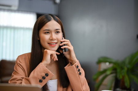 Confident and gorgeous Asian businesswoman or female executive manager on the phone with her client, dealing a business work on the phone.の写真素材
