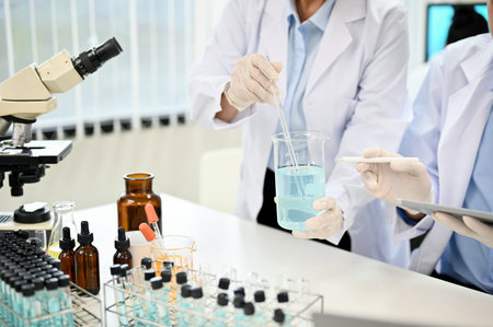 Two expert female scientist in white gown working and testing a new chemical sample together in the...